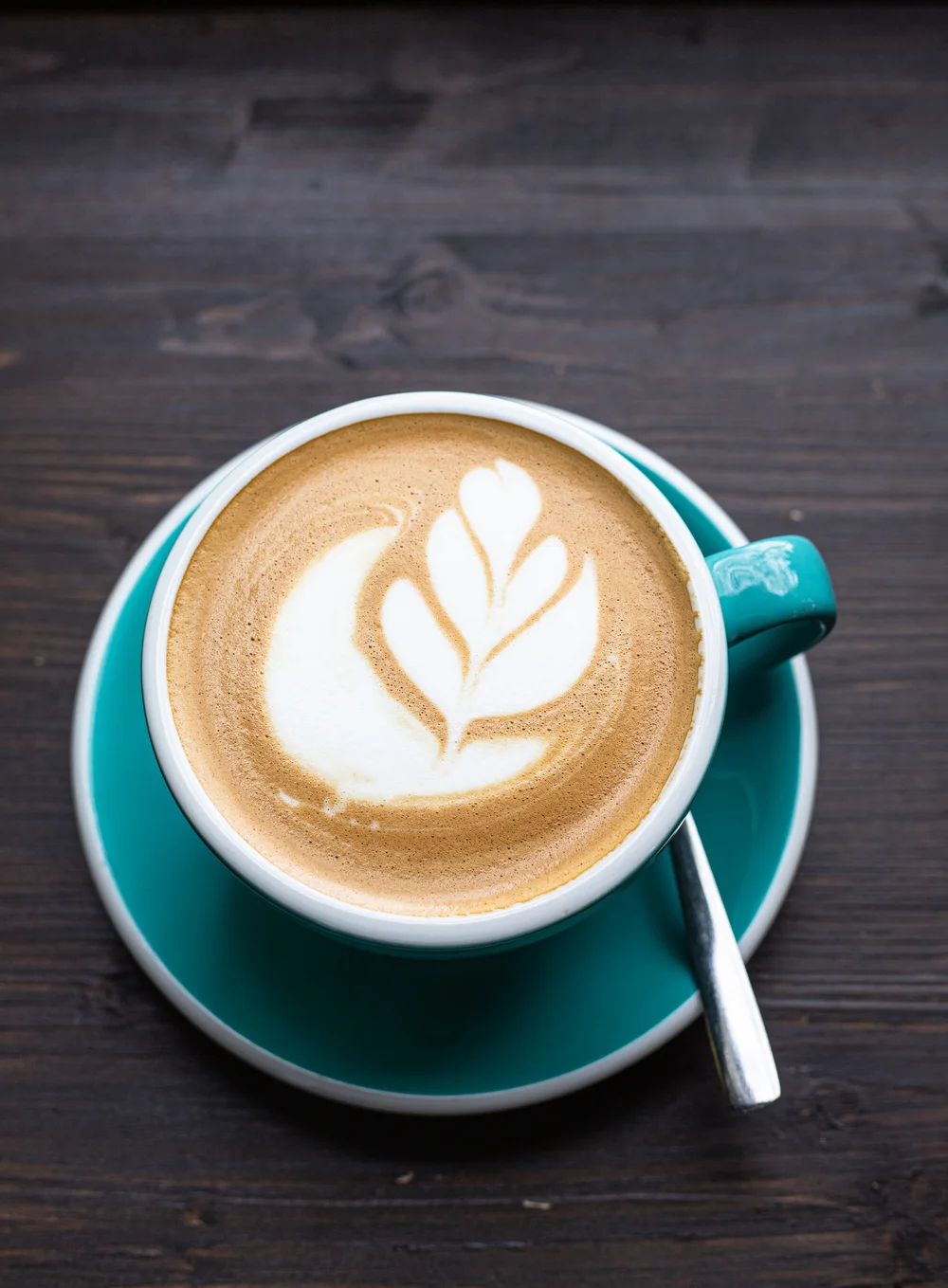 Coffee with latte art in ceramic cup on wooden table in cafe or coffee shop. Top view.